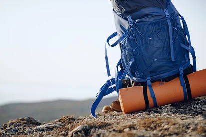 Hiking backpack with outdoor essentials on a rock