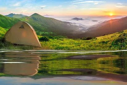 Modern camping tent near a forest lake